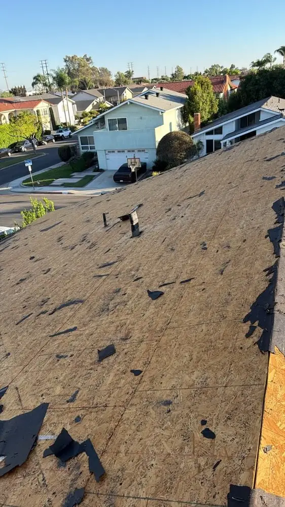 Shingle tear-off in progress on a two-slope residential roof